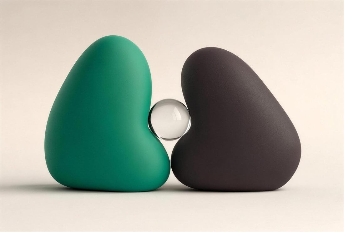 Two rounded forms leaning toward one another with a clear glass sphere resting between them.